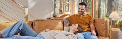 An expecting couple rests on a sofa.