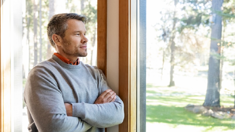 A person with a confident expression gazes out a window.