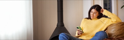 A person relaxes on a chair and looks at a mobile phone.