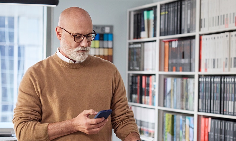A professional looking at their phone in their office.