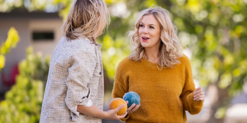 Two people, each holding a bocce ball, talk to each other.
