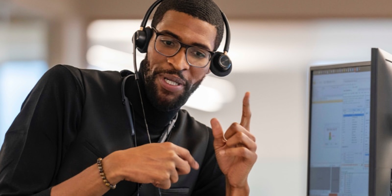 A business person speaks over the phone using a headset.