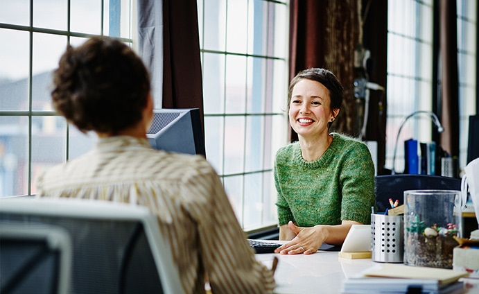 Two women sitting at across from each other at a desk