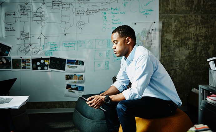 Man sitting in front of whiteboard staring down at a tablet