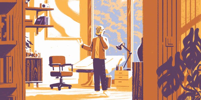 An older man talking on the phone in his home office.
