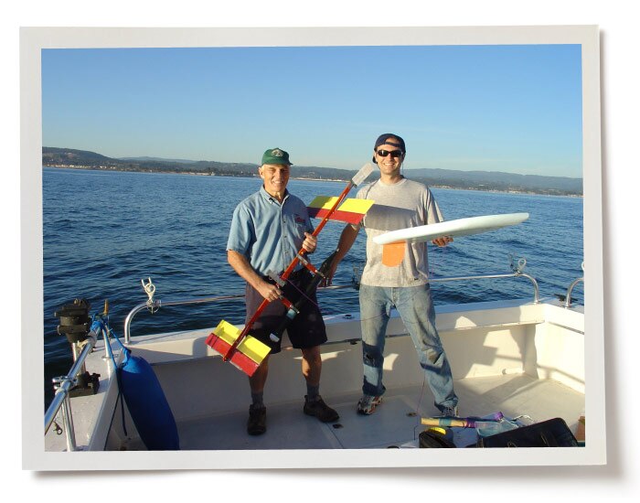Two men standing on a boat in Monterey Bay and holding a prototype of the Wave Glider.
