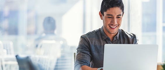 Person smiling while sitting and working on a laptop.